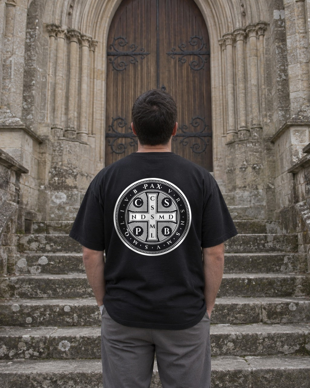 St. Benedict Medal tee outside a church, back view
