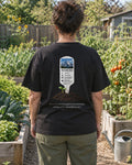 Mustard Seed Plant Tag tee in a vegetable garden, back view