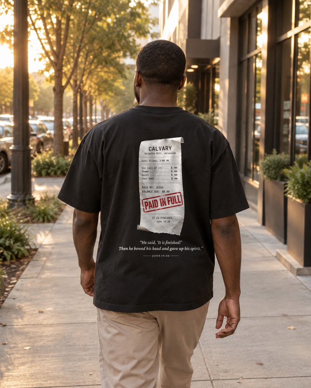 Paid in Full Receipt tee on a city sidewalk, back view