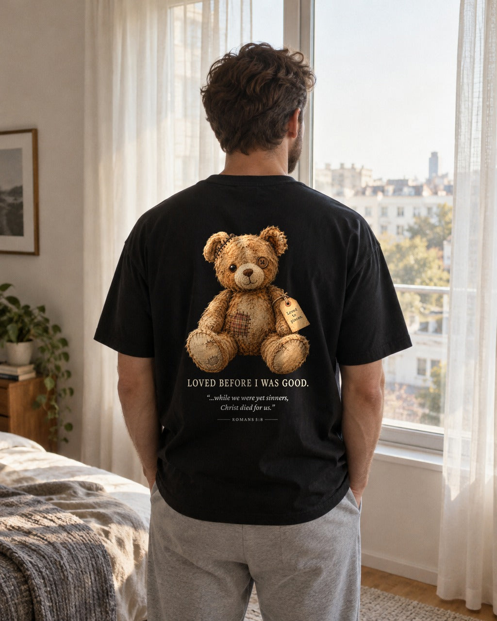 Loved Before I Was Good Teddy tee by a bedroom window, back view